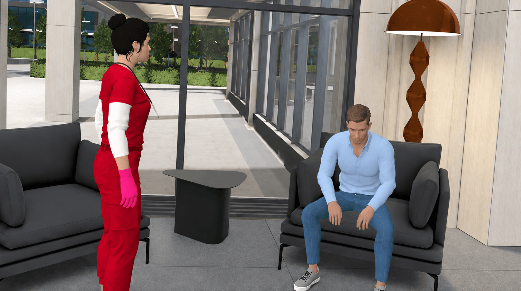 A staff member in red scrubs and pink gloves stands talking with a man seated on a lobby sofa.