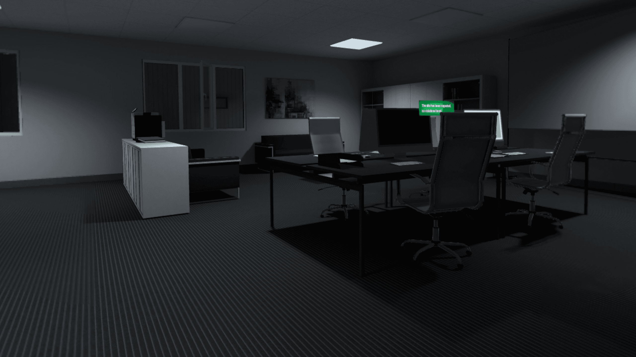 A dimly lit open-plan office with desks, monitors and chairs, a sign on the wall reading that the site has been inspected with no violations found.